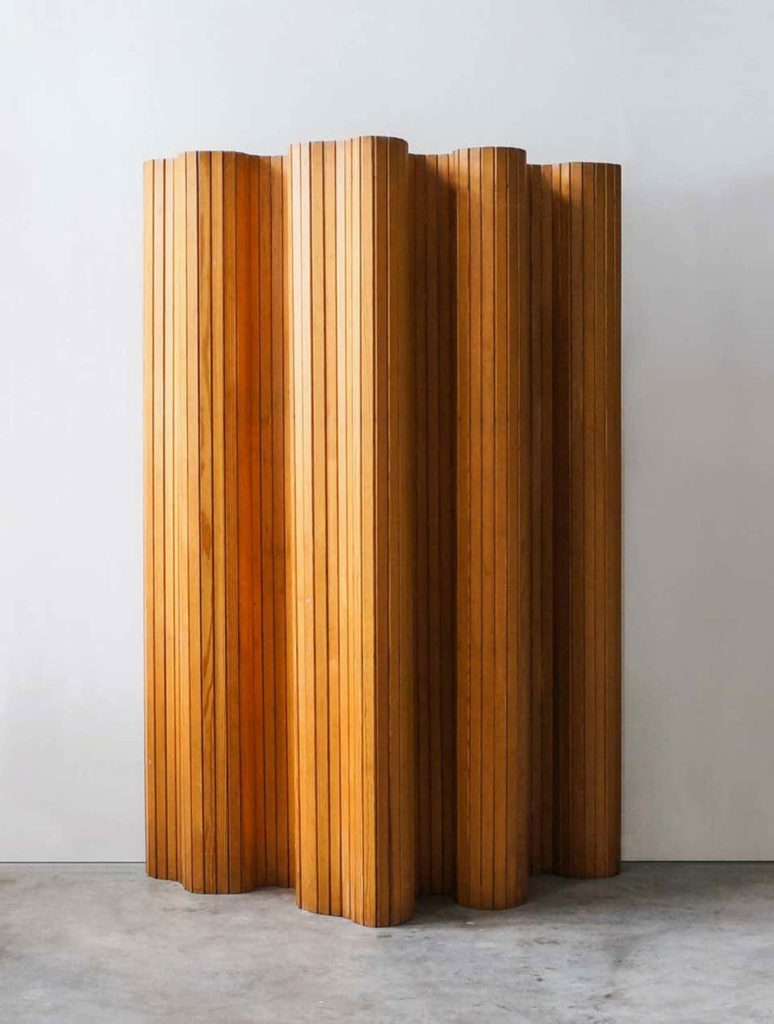 Estructura de lamas de madera formando una figura ondulada. Poppyns Magazine