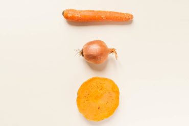 Foto cenital de una zanahoria, una cebolla y media calabaza. Poppyns Magazine