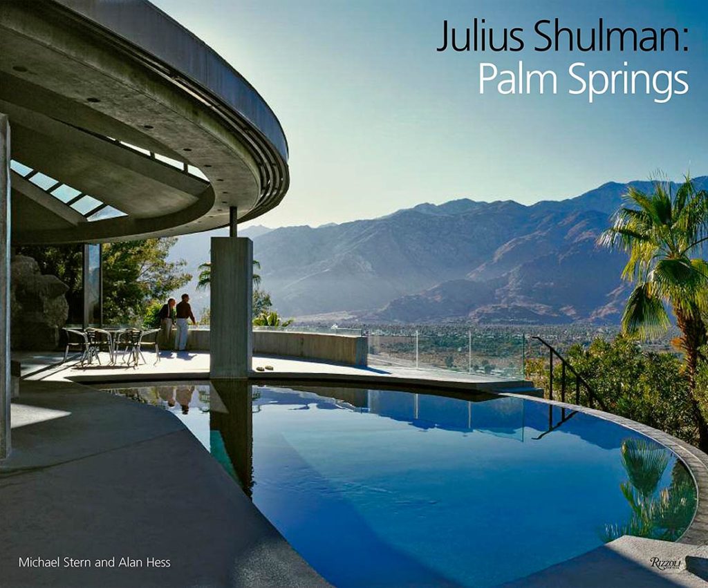 Portada de publicación con una edificación minimalista con piscina infinity y vistas a las montañas, con dos hombres apoyados en la barandilla y con título Julius Shulman: Palm Springs. Poppyns Magazine