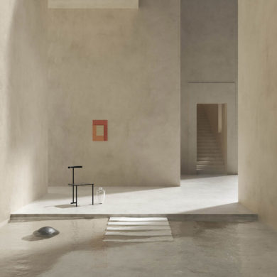 Interior de edificio con paredes de piedra lisas, un cuadro rojo sobre una pared, una puerta al fondo con unas escaleras ascendentes, una silla de forja junto a un jarrón de cristal y una piscina de agua clara con escalera de obra. Poppyns Magazine