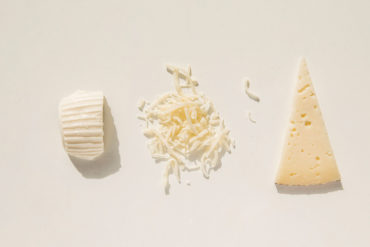 Tres tipos de quesos, uno cortado en triángulo, uno rayado y otro fresco. Poppyns Magazine