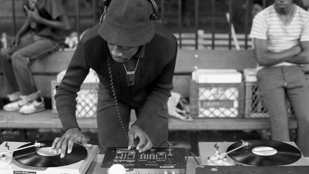 Fotografía antigua de Dj afroamericano mezclando música en vinilo.