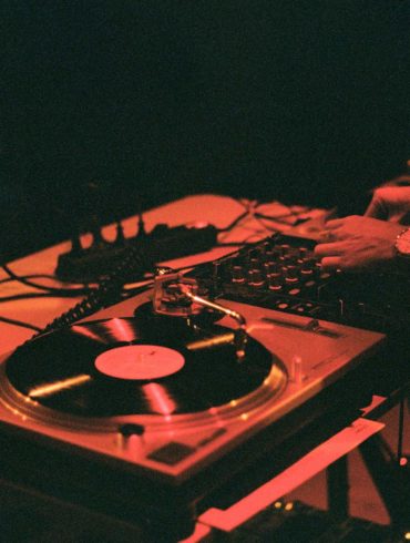Fotografía luz roja de DJ mezclando música con vinilos