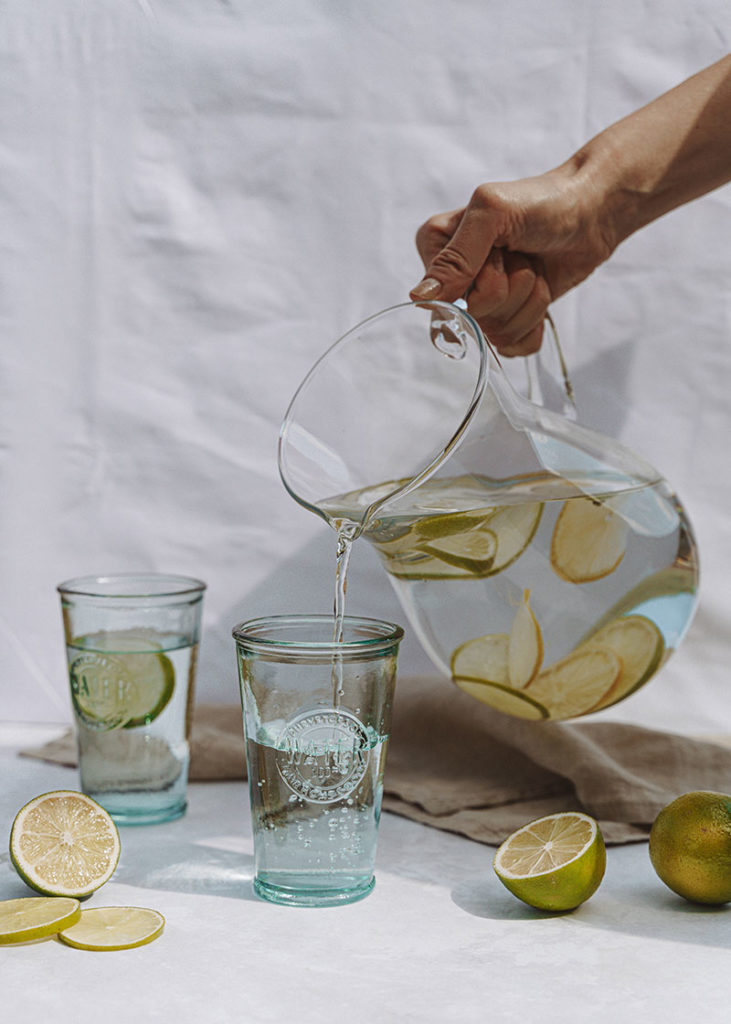 Sirviendo agua con limón en vasos de vidrio