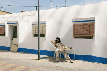 Mujer sentada en mesa al sol con refresco.